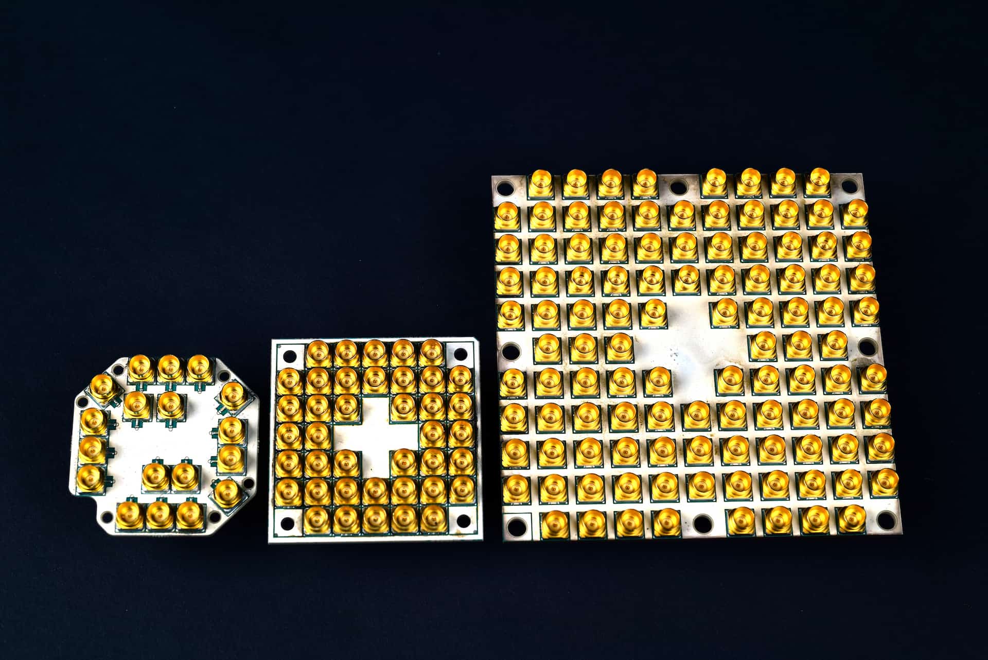 Intel Corporation is making fast progress scaling superconducting quantum computing test chips to higher qubit counts -- from 7, to 17 and now 49 qubits (left to right). Multiple gold connectors are required to control and operate each qubit. (Credit: Walden Kirsch/Intel Corporation