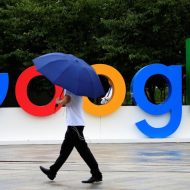Une personne avec un parapluie marchant à côté du logo de Google