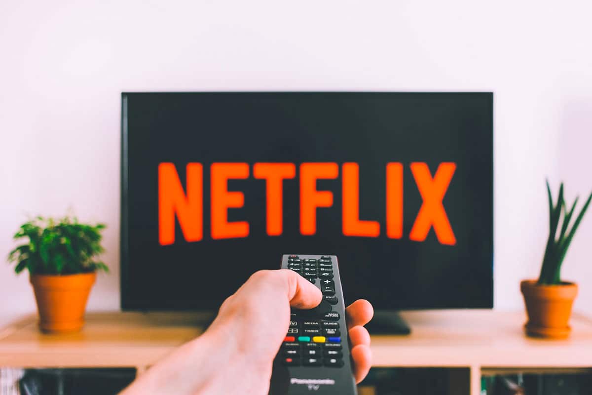 Netflix le logo sur une TV avec une personne qui tient sa télécommande