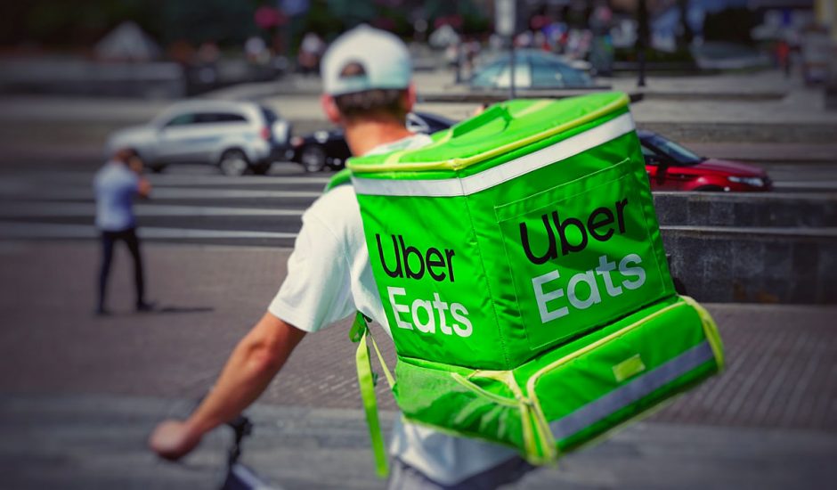 Un livreur avec un sac à dos Uber Eats à vélo dans la rue.