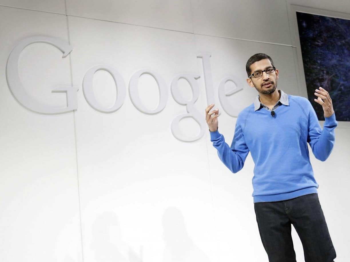 Le CEO de Google, Sundar Pichai, se tient devant le logo de son entreprise.