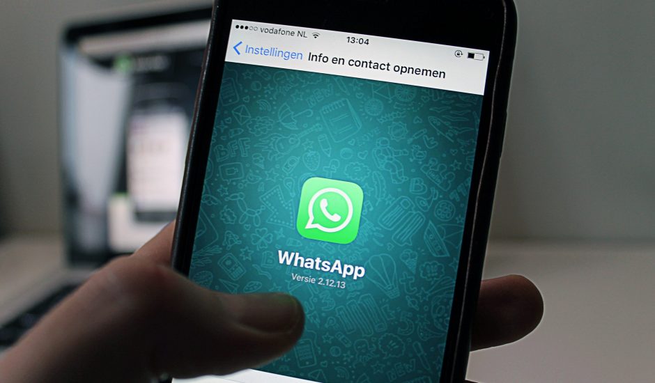 Une personne tient un smartphone sur lequel s'affiche le logo de WhatsApp.