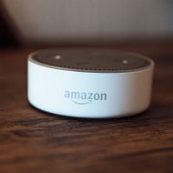 Un appareil Echo Dot d'Amazon posé sur une table en bois.