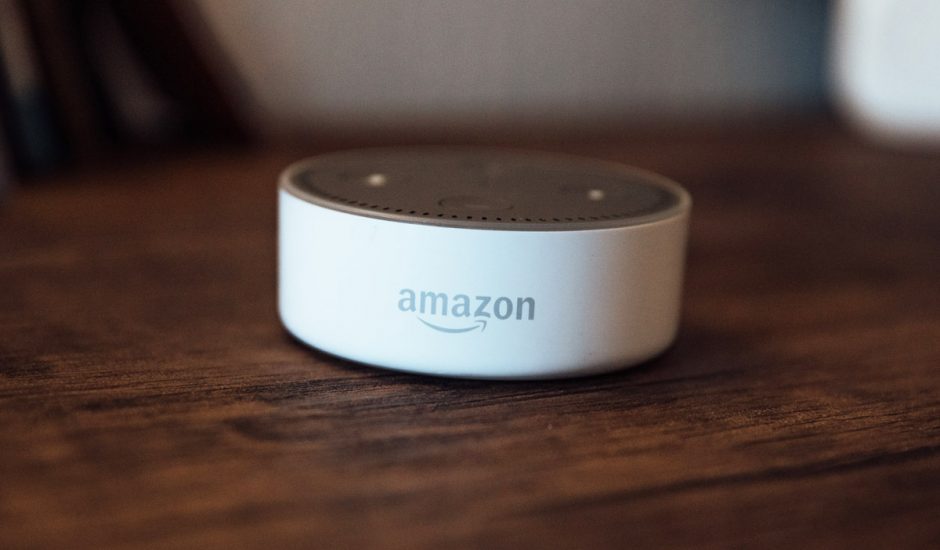 Un appareil Echo Dot d'Amazon posé sur une table en bois.