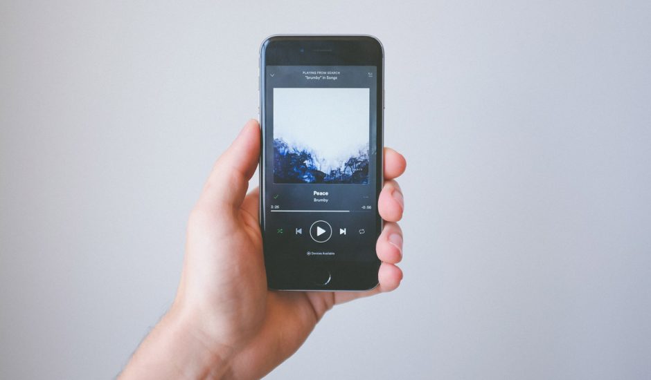 Une personne tient un smartphone dans la main avec l'application Spotify en fonctionnement.