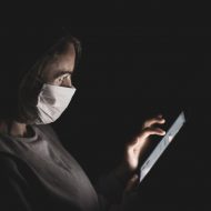 Une femme avec un masque chirurgical regardant son téléphone