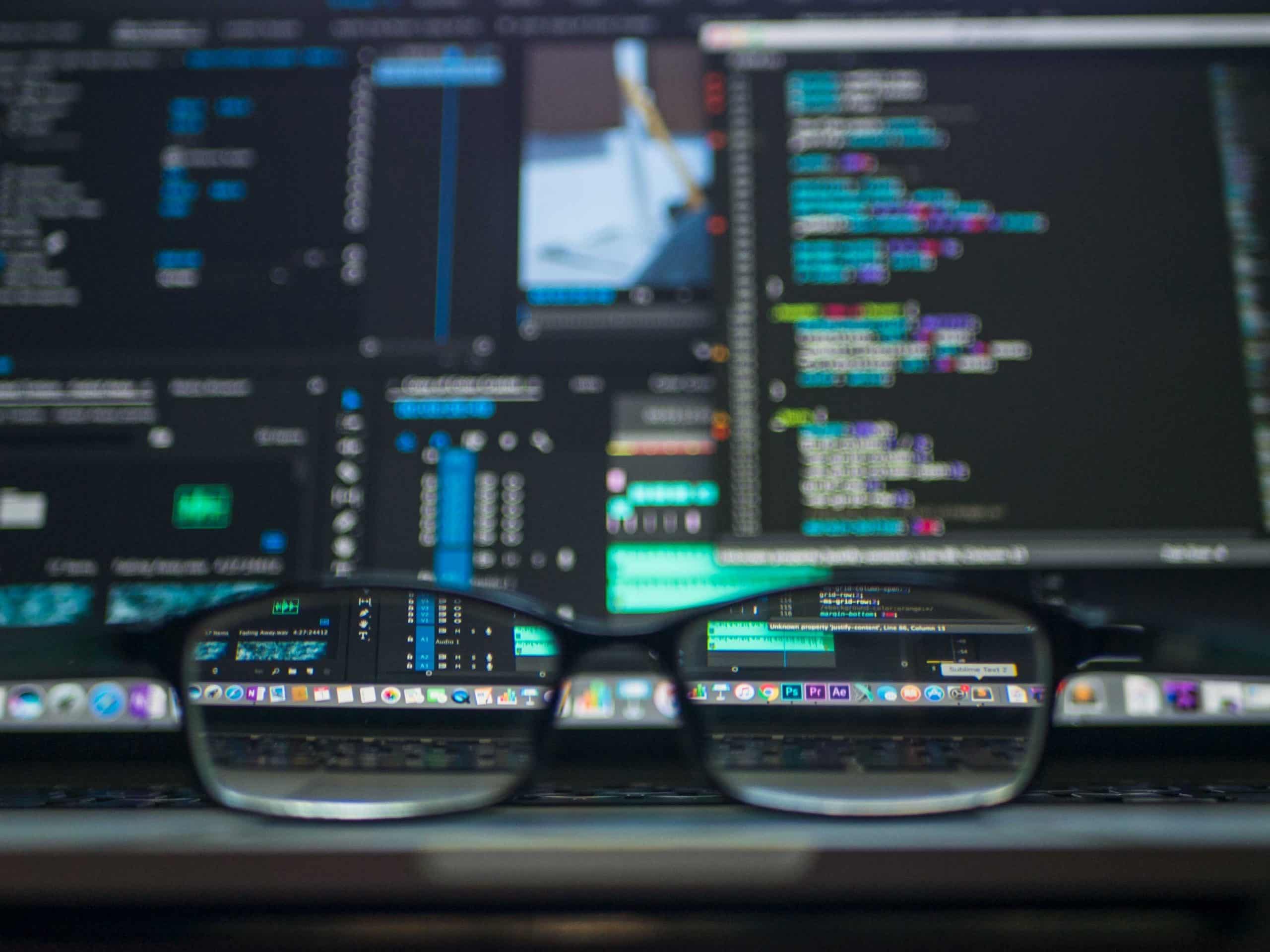 Des lunettes de vue posées devant un écran affichant du code informatique
