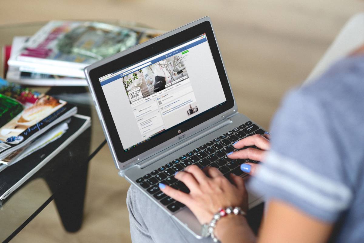 Une femme avec un ordinateur portable ouvert sur le réseau social Facebook.