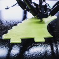 Une imprimante 3D est en train d'imprimer une structure jaune.