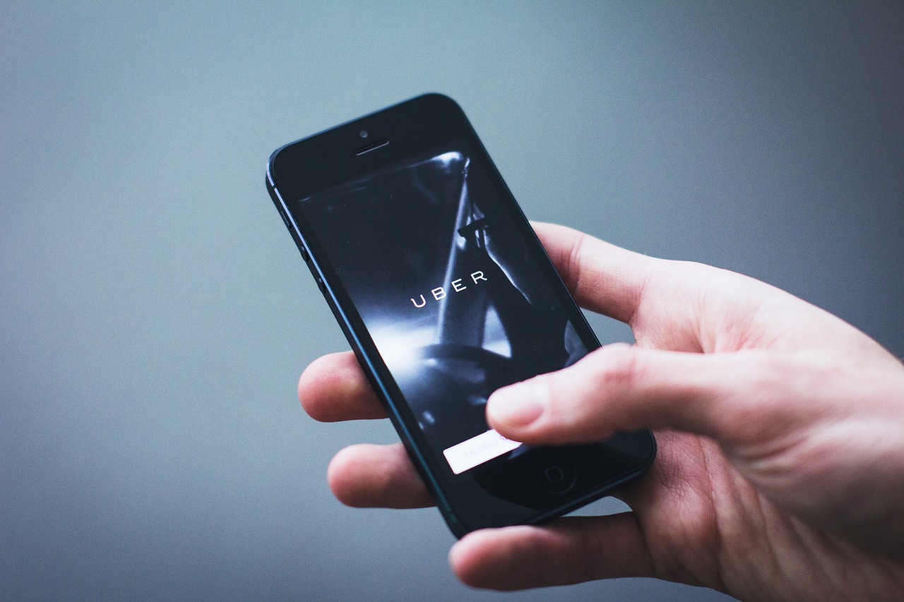 Une main tenant un smartphone ouvert sur l'application Uber.