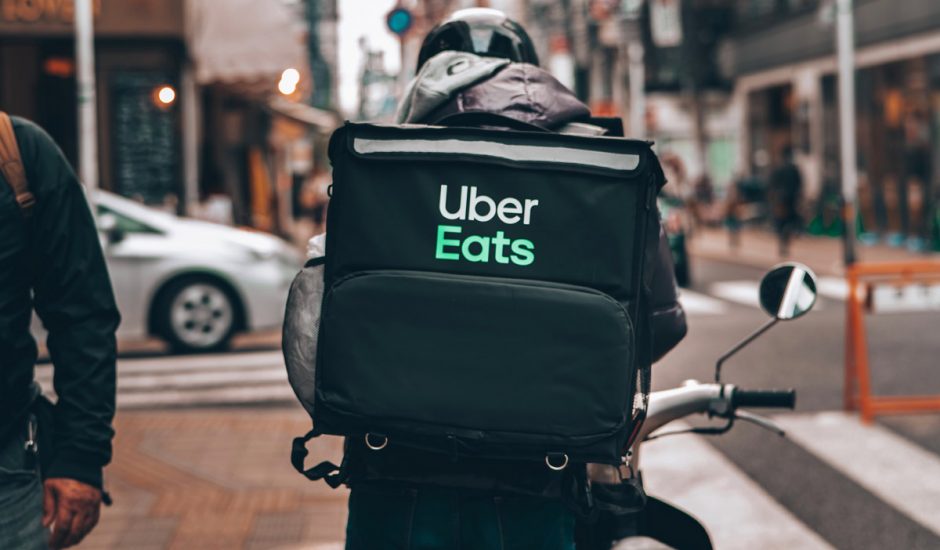 Un livreur Uber Eats de dos dans la rue.