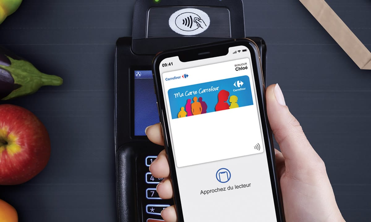 Un téléphone mobile avec la carte de fidélité Carrefour dans Apple Pay effectue un paiement sans contact sur un TPE.