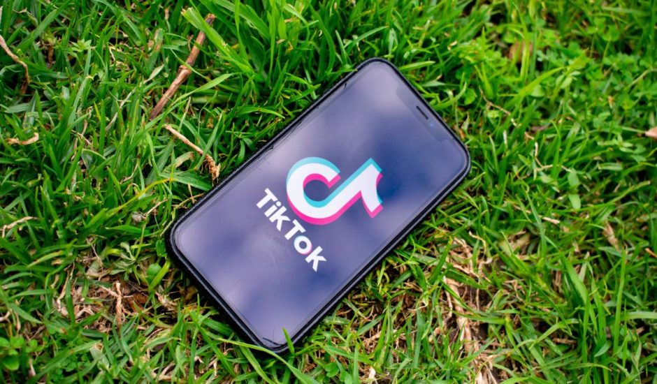 Un smartphone posé sur du gazon sur lequel apparaît le logo de TikTok.