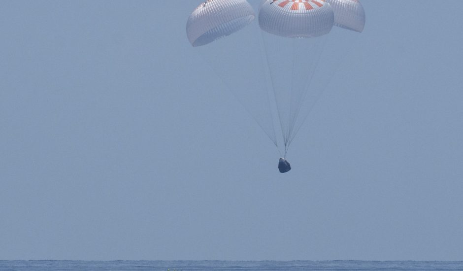 La capsule Crew Dragon avec ses quatre parachutes déployés sur le point de se poser sur la mer
