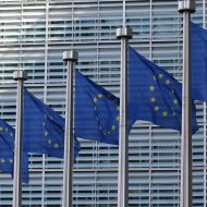 Plusieurs drapeaux de l'Union Européenne flottent devant un building.