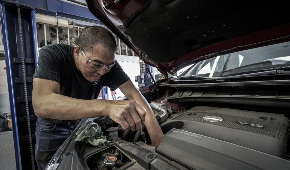 Un garagiste répare le moteur d'une voiture.