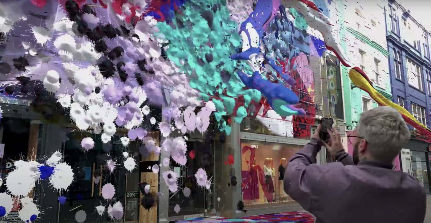 Un homme projette de la peinture sur la façade de bâtiments grâce à son smartphone.