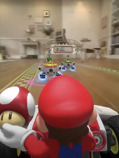 Le personnage Mario est dans un karting, tient un champignon dans la main et parcourt un circuit dans un salon.