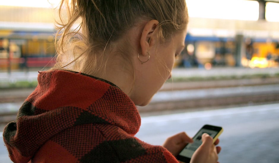 Une jeune femme utilise une application de messagerie instantanée sur son smartphone.