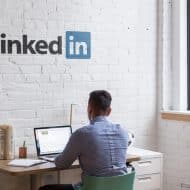 Un homme assis à son bureau avec le logo LinkedIn sur le mur.