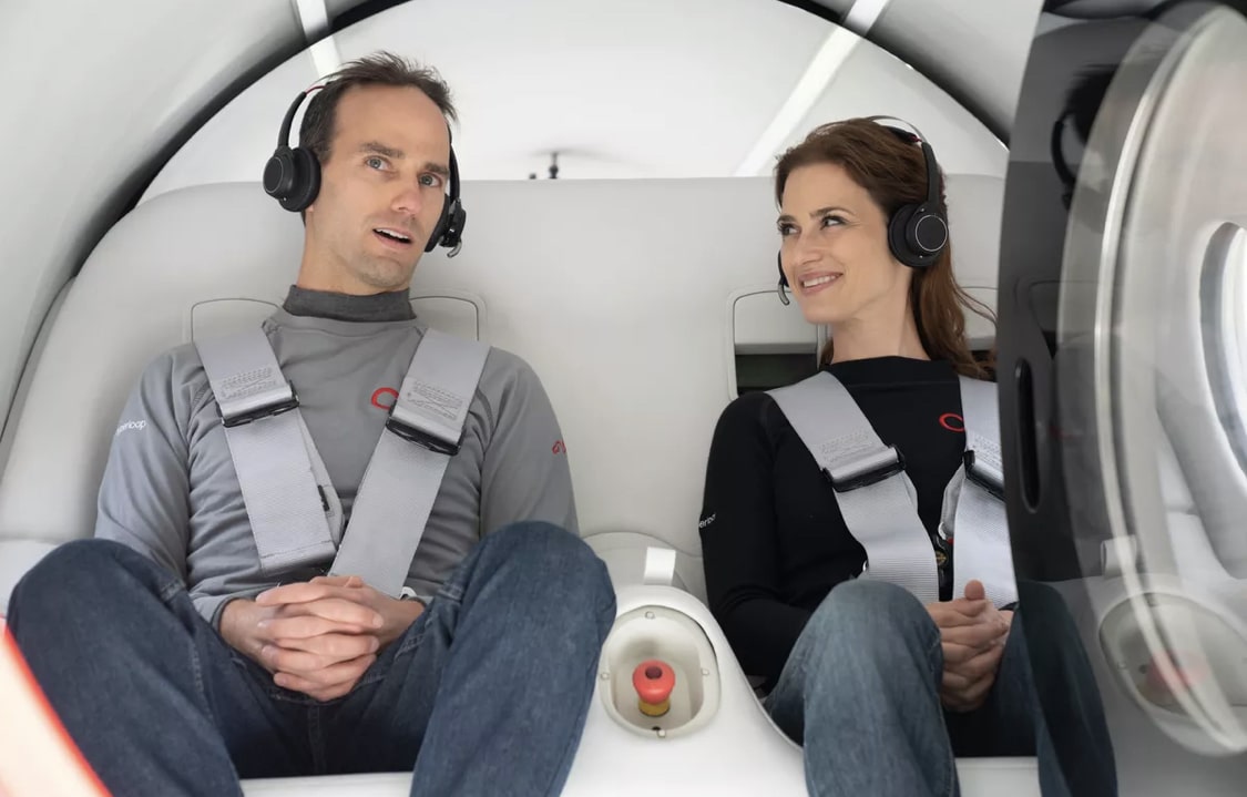 Un homme et une femme assis dans une capsule de Virgin Hyperloop.