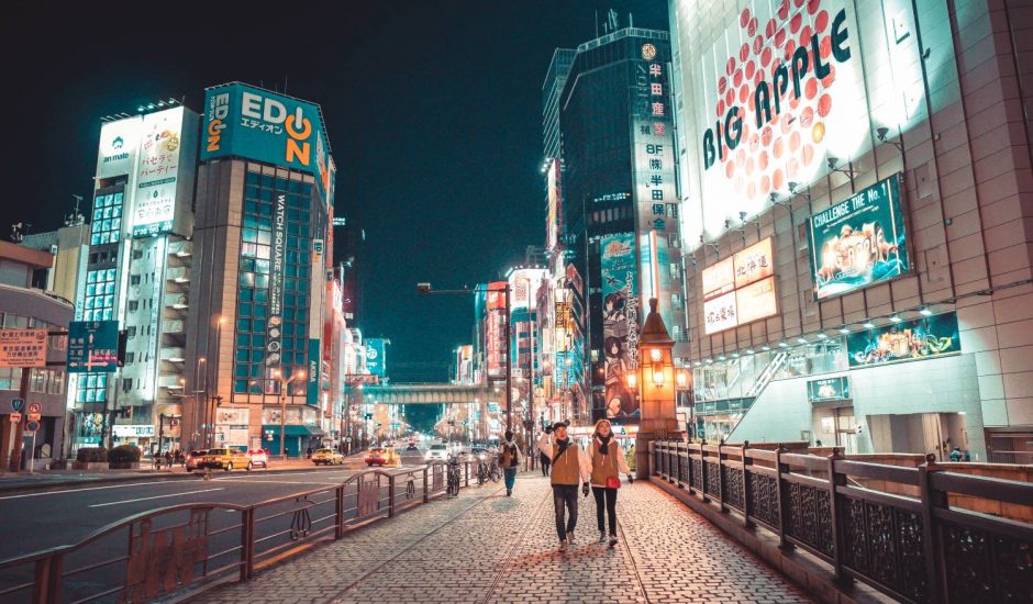 Un couple marche dans les rues illuminées d'une ville japonaise.