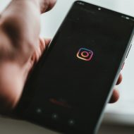 Un homme tenant un smartphone affichant le logo Instagram.