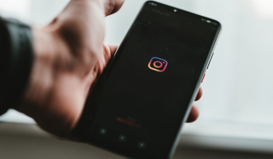 Un homme tenant un smartphone affichant le logo Instagram.
