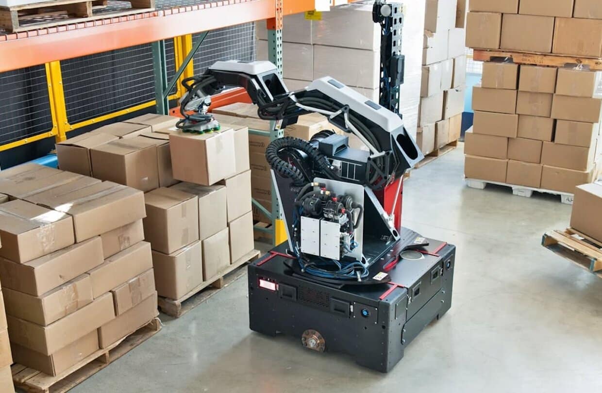 Le robot Stretch de Boston Dynamics soulève des cartons dans un entrepôt.