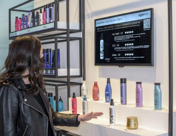une femme pointant du doigt un produit qui apparaît sur l'écran en face d'elle dans l'Amazon Salon