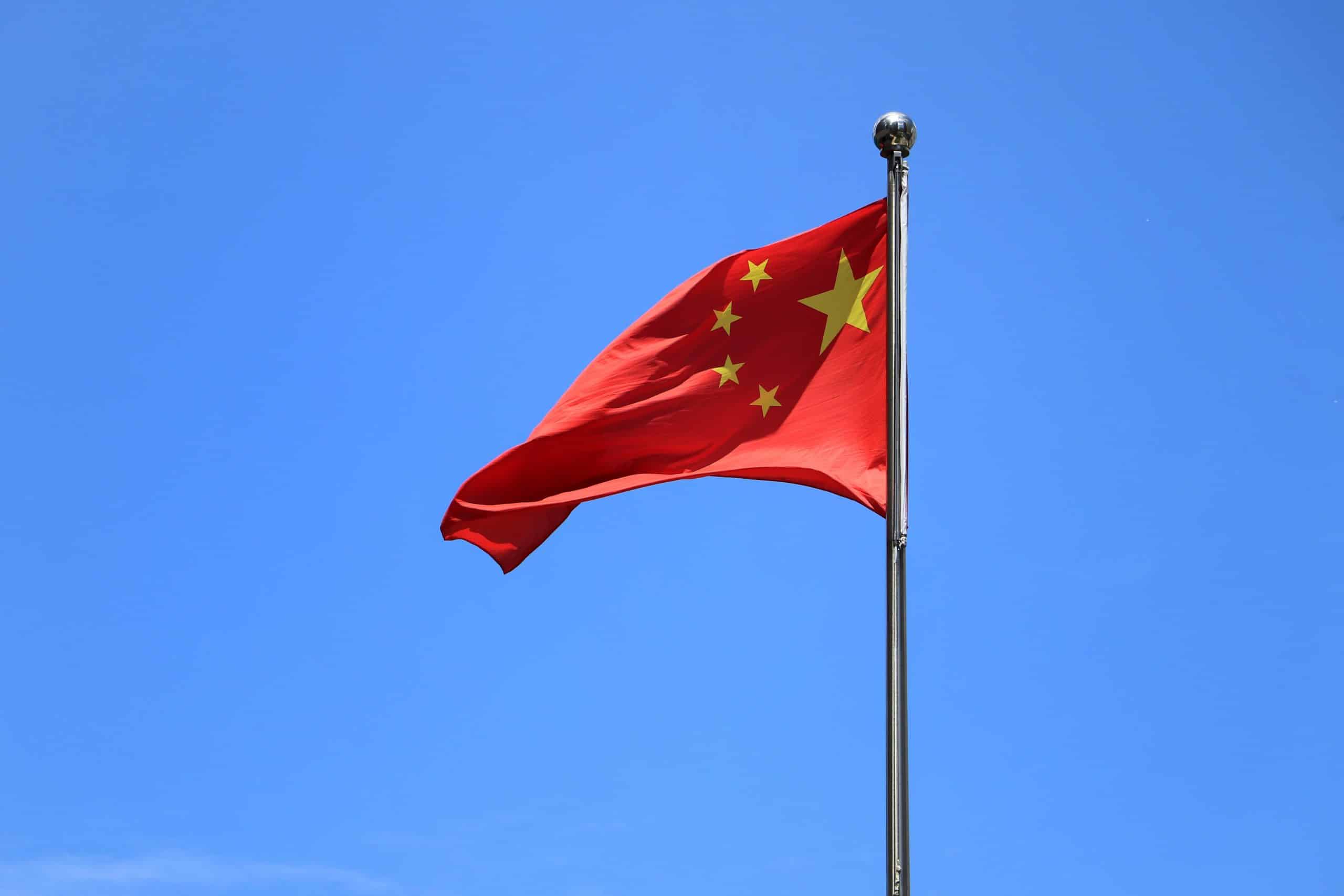 Le drapeau chinois flotte devant un ciel bleu.