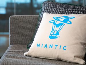 Un coussin arborant le logo de Niantic posé sur un canapé.