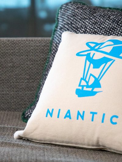 Un coussin arborant le logo de Niantic posé sur un canapé.