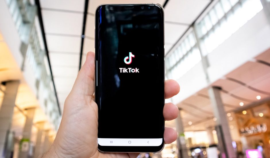 Un homme tient un smartphone affichant l'application TikTok.