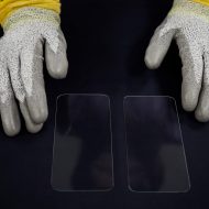 Des mains portant des gants travaillent sur le verre d'écrans.