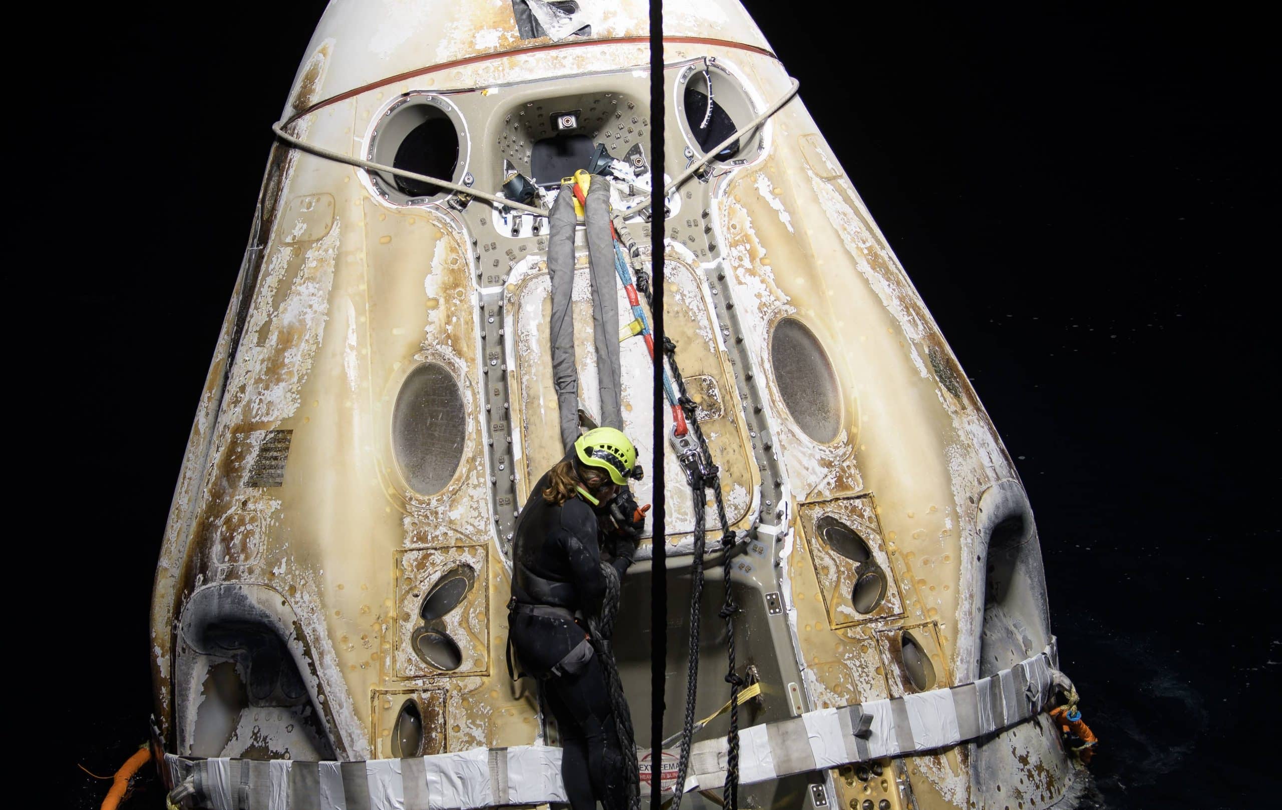 La capsule Crew Dragon flottant sur l'eau quelques minutes après son arrivée sur Terre, alors que le personnel de SpaceX travaille à son ouverture.
