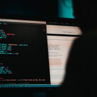 Un homme de dos en train de coder sur un ordinateur.