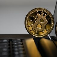 Photographie d'un bitcoin tenant en équilibre sur un ordinateur portable.