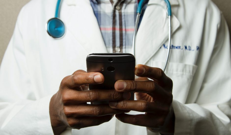 Photographie d'un médecin tenant un smartphone probablement en train d'utiliser une IA de santé.