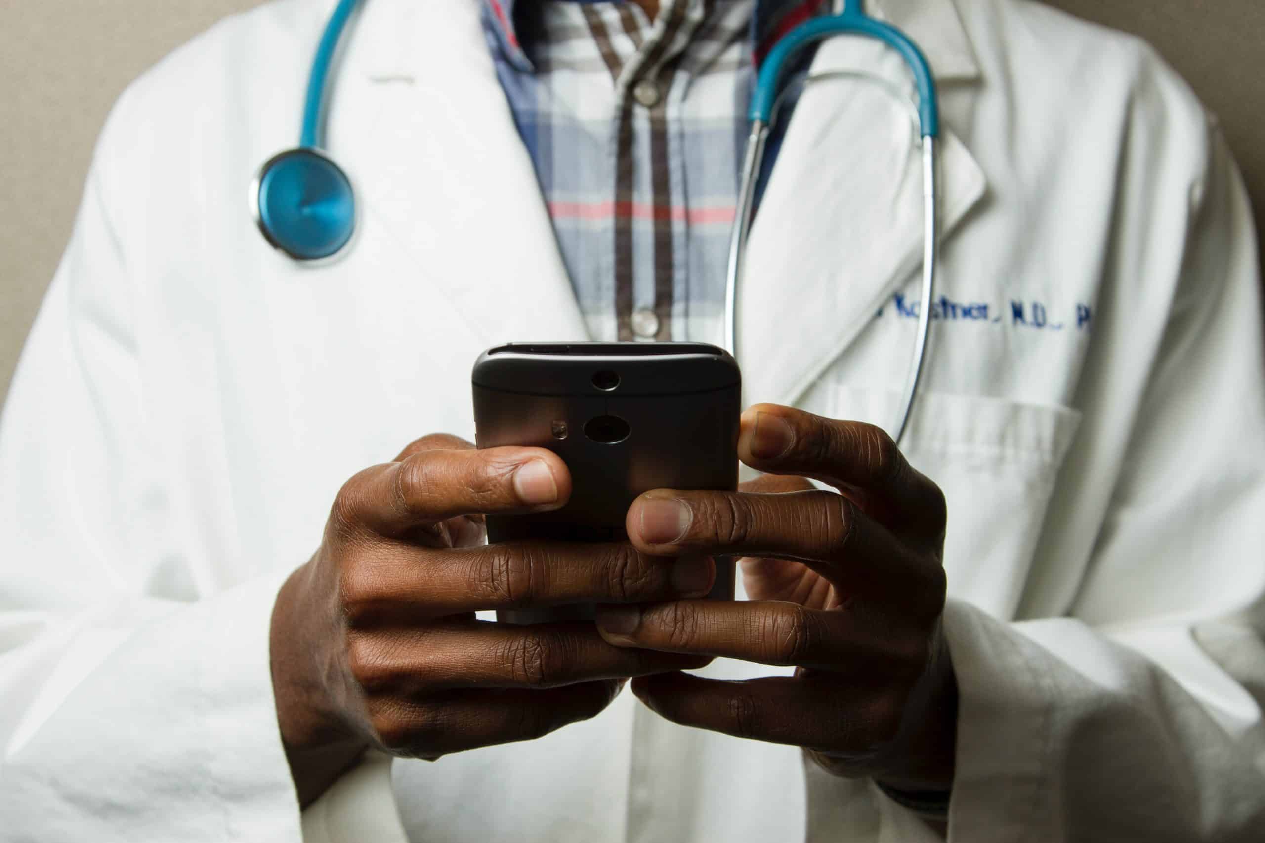 Photographie d'un médecin tenant un smartphone probablement en train d'utiliser une IA de santé.