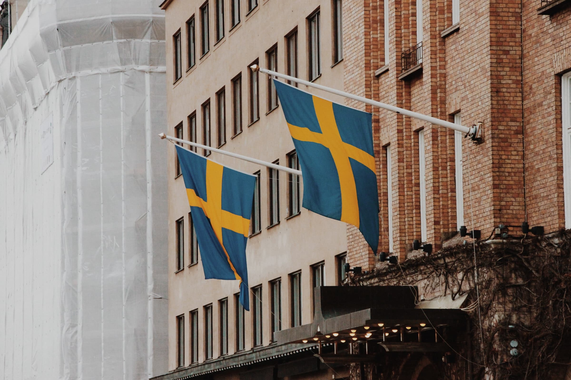 Photographie de deux drapeaux suédois sur un bâtiment.