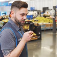Un employé de Walmart tenant un smartphone dans sa main.
