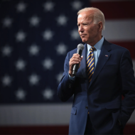 Joe Biden avec un micro devant le drapeau américain