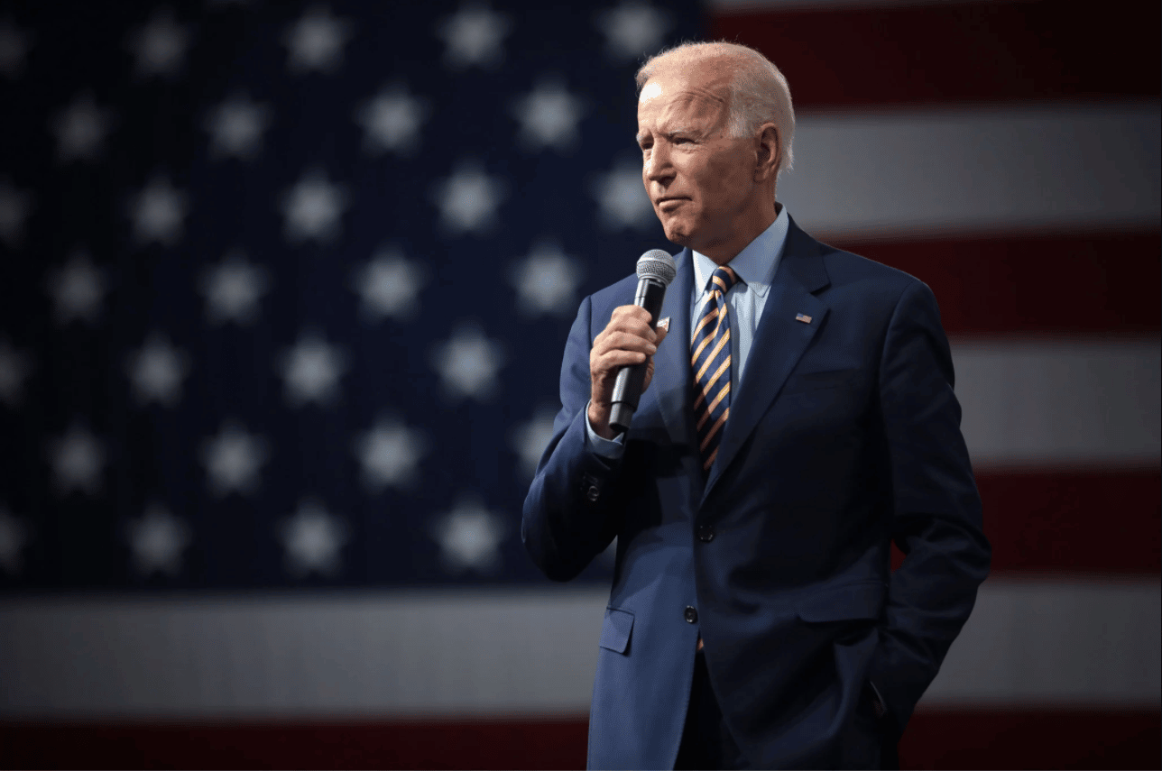 Joe Biden avec un micro devant le drapeau américain