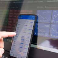 Photographie d'un ordinateur et d'un smartphone présentant des indices boursiers.