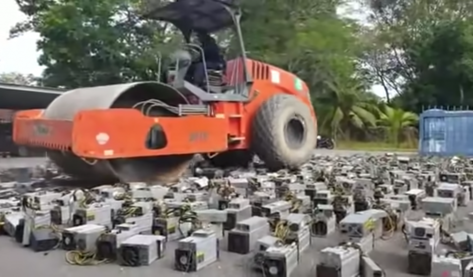 Un bulldozer écrasant des kits de minage de cryptomonnaies