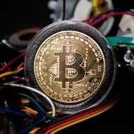 Photographie d'un bitcoin présenté avec des fils électriques rappelant le minage.