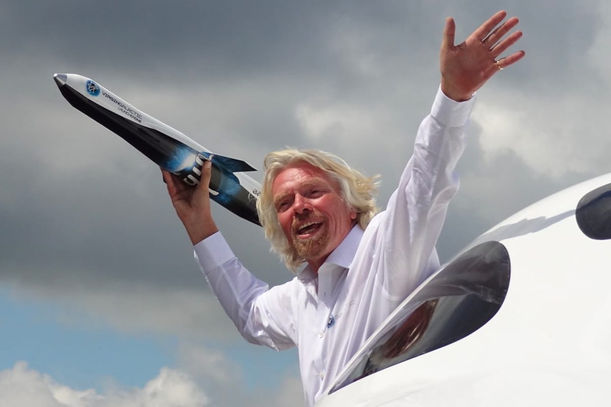 Portrait de Richard Branson tenant la maquette d'une fusée dans sa main.