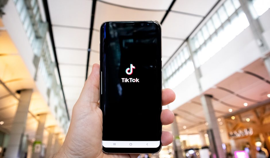 Une personne tient un smartphone affichant l'application TikTok.