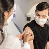 Une infirmière met un pansement sur le bras d'un homme après un vaccin.